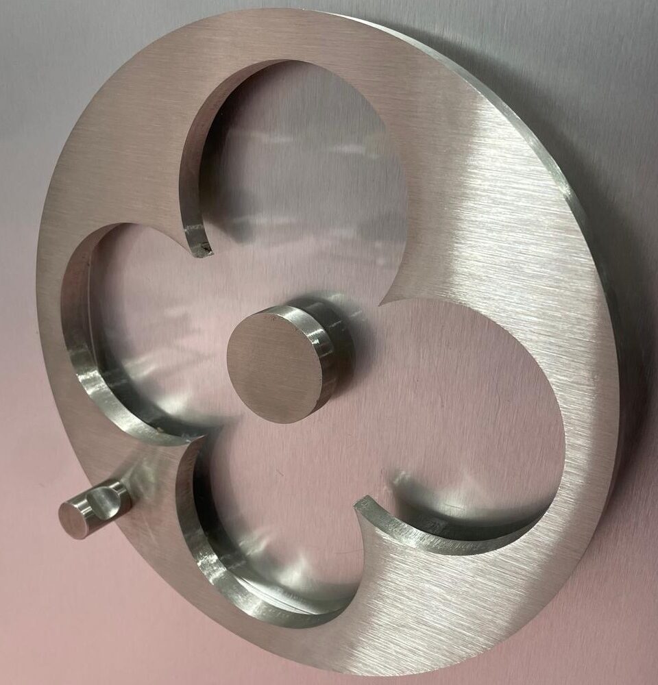 Élément décoratif en métal usiné, fabrication sur mesure pour projet architectural ou signalétique.