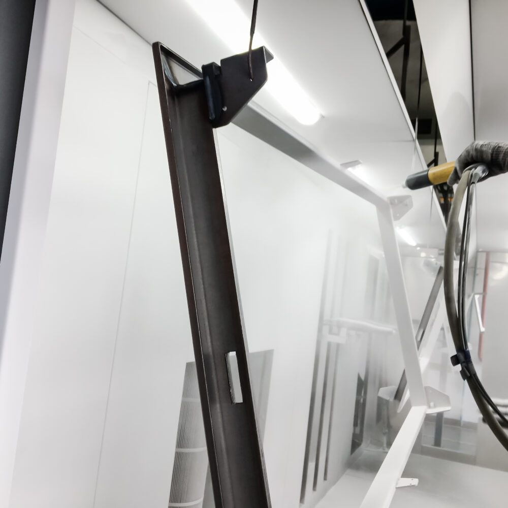 Pièce en acier suspendue en cabine de thermolaquage avant application de la peinture poudre.